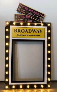 the broadway sign is lit up in front of a white wall with lights on it