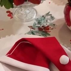 there is a red and white napkin on the table with strawberries in vases behind it