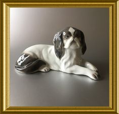 a dog figurine sitting on the ground in front of a gold frame