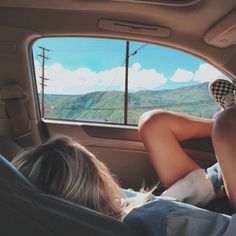 two people sitting in the back seat of a car looking out at mountains and hills