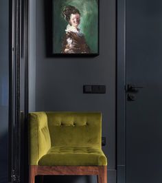 a green chair sitting in front of a painting on the wall next to a doorway