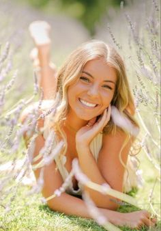 a woman laying on the ground in front of lavender flowers