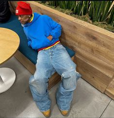 a man sitting on top of a bench next to a wooden table