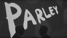 two men standing next to each other in front of a wall with the word parley painted on it