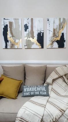 three paintings hang on the wall above a couch in a living room with yellow pillows