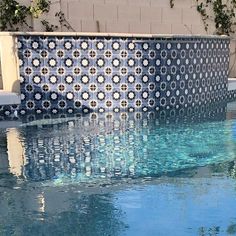 an outdoor swimming pool with blue and white tiles on the wall next to it's edge