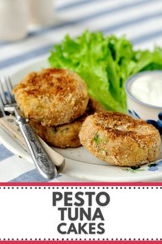 two crab cakes on a white plate with lettuce and sauce next to it