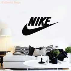 a living room with a white couch and black nike wall decal