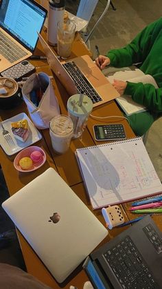 two laptops are sitting on a table with papers and other items around it,