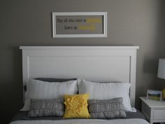 a bed with white sheets and yellow pillows in a gray room next to a window