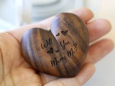 two heart shaped wooden pieces with writing on them in someone's hand that says, will you marry me?