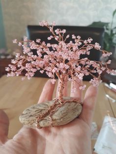 a hand holding a small tree made out of cookies on top of a wooden table