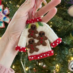 a hand is holding a christmas ornament with two dogs on it, hanging from a tree