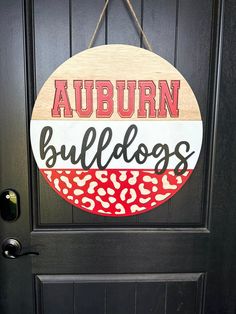 a wooden sign that says auburn bulldogs hangs on the front door to a black door