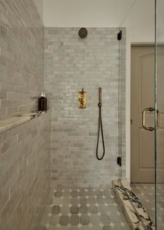 a walk in shower sitting next to a tiled wall