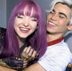 a woman with purple hair hugging a man