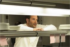 a man standing in front of stacks of white plates on top of a kitchen counter