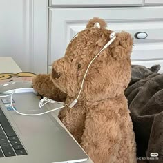 a teddy bear sitting in front of a laptop computer with headphones attached to it