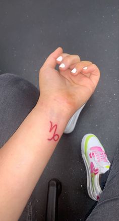 a woman's arm with a small red tattoo on her left wrist and foot