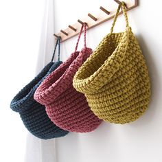 three crocheted baskets hanging on the wall