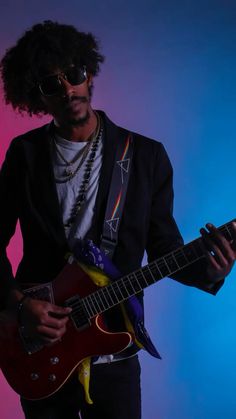 a man with curly hair playing an electric guitar in front of a pink and blue background