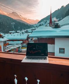 an open laptop computer sitting on top of a wooden table in front of a window