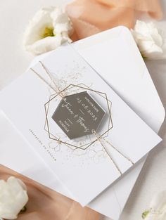 an open envelope with a wedding card on it and some white flowers in the background