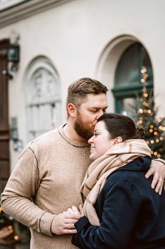 a man and woman standing next to each other in front of a christmas tree