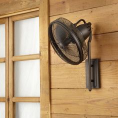 an old fashioned fan mounted on the side of a wooden wall