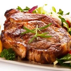 steak and vegetables on a white plate with oranges, lettuce and tomatoes