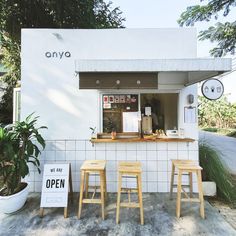 an outdoor coffee shop with three stools and a sign that says, we are open