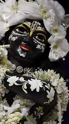 a close up of a statue with flowers in it's hair and face painted black