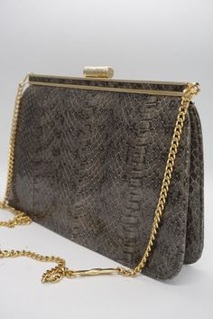 Vintage Clutch Bag with a snake skin effect. With a chain handle in a very pretty tone of gold (not yellow), this bag is perfect to complement your outfit giving it a classic touch. It opens and closes with a hinge and has a small zippered pocket inside. A personality-packed choice for days when you want to travel light but make a statement. PERFECT CONDITION - LIKE NEW LENGHT: 15 cm WIDTH: 22 cm DEPTH: 7 cm HANDLE LENGHT: 90 cm NATURAL LEATHER MADE IN SPAIN Elegant Leather Bag With Snake Print, Elegant Leather Snake Print Bags, Elegant Snake Print Leather Bags, Elegant Rectangular Bag With Snake Print, Luxury Evening Bag With Snake Print, Classic Party Bag With Chain Detail, Luxury Snake Print Evening Bag, Elegant Rectangular Snake Print Bag, Elegant Snake Print Rectangular Bags