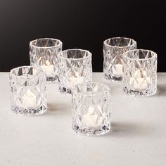 four clear glass candlesticks sitting next to each other on a white counter top