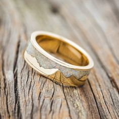 a wedding band with an image of the mountains on it is sitting on a wooden surface