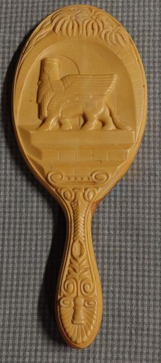 a wooden spoon with an animal carved on the top and bottom, sitting on a gray surface