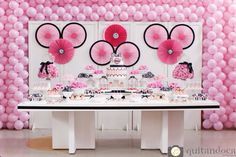 a table topped with lots of pink and white balloons next to a wall covered in minnie mouse decorations