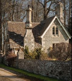 an old stone house with chimneys on the roof and brick walls in front of it