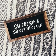 a wooden sign that says so fresh and so clean on top of a patterned rug