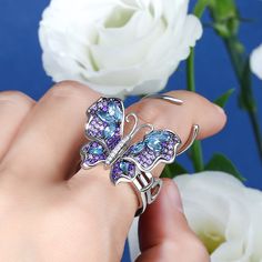 Our gorgeous flying butterfly ring, with its distinctive workmanship, pays tribute to the glamour and elegance of this creature. Through its graceful movement between your fingers, it recreates the fluttering charm of wings and adds unique enchantment to your femininity. Combing beautiful colors and asymmetry, this dazzling piece highlights eight brilliant marquise-cut blue stones, and smaller round stones in purple paved on wings. The multi-colored butterfly, fashioned in fine sterling silver, Luxury Butterfly Shape White Gold Jewelry, Luxury Butterfly White Gold Jewelry, Luxury Butterfly Shaped White Gold Jewelry, Luxury White Gold Butterfly Jewelry, Luxury White Gold Butterfly Ring, Silver Butterfly Fine Jewelry, Fine Jewelry Butterfly Piece For Wedding, Silver Jewelry With Butterfly Charm, Fine Jewelry Butterfly Shape For Wedding