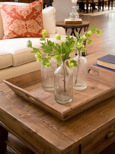 three vases with flowers are sitting on a tray in the middle of a living room