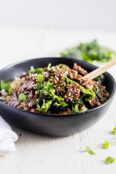 a bowl filled with meat and broccoli on top of a white tablecloth