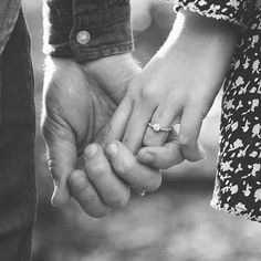 black and white photograph of two people holding each other's hands with their fingers