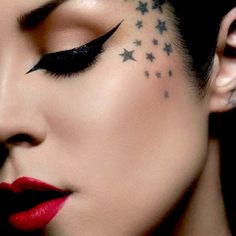 a woman with stars on her face and black makeup is looking down at the camera