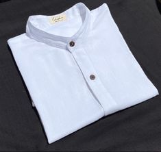 Mandarin collar shirt White  What distinguishes our shirt? There are several details that make our shirt unique. Like the rest of our collection, it is made of cotton and bamboo, two natural fibers that when put together give us a very soft texture. It is the shirt that you will not want to take off for its high comfort and freshness. Flax and bamboo have many benefits for the planet and for those who use them. Both materials are friendly to the skin, in addition to being hypoallergenic, they protect against UV rays. The buttons are made of shell. Every detail of this piece is natural, ecological and biodegradable. * Important: you can choose to order it in black, white, army green, gray / purple, brown and blue. * You can also indicate if you want it with a line or without a line and the Classic White Shirt With Stand Collar, Traditional White Linen Shirt, White Linen Shirt With Buttons, Mandarin Collar Blouse, Mandarin Collar Shirt, Blouse White, Collar Blouse, Collar Shirt, Soft Texture