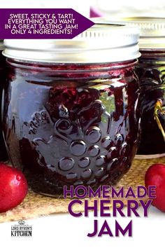 three jars filled with jam sitting on top of a wooden cutting board next to two cherries