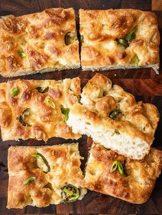 several slices of pizza sitting on top of a wooden cutting board with cheese and green peppers