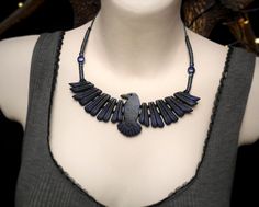 a woman wearing a black necklace with blue beads and a bird pendant on it's neck