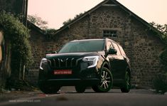 a black suv parked in front of a stone building