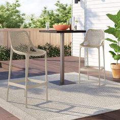 two chairs sitting on top of a rug next to a table and potted plant